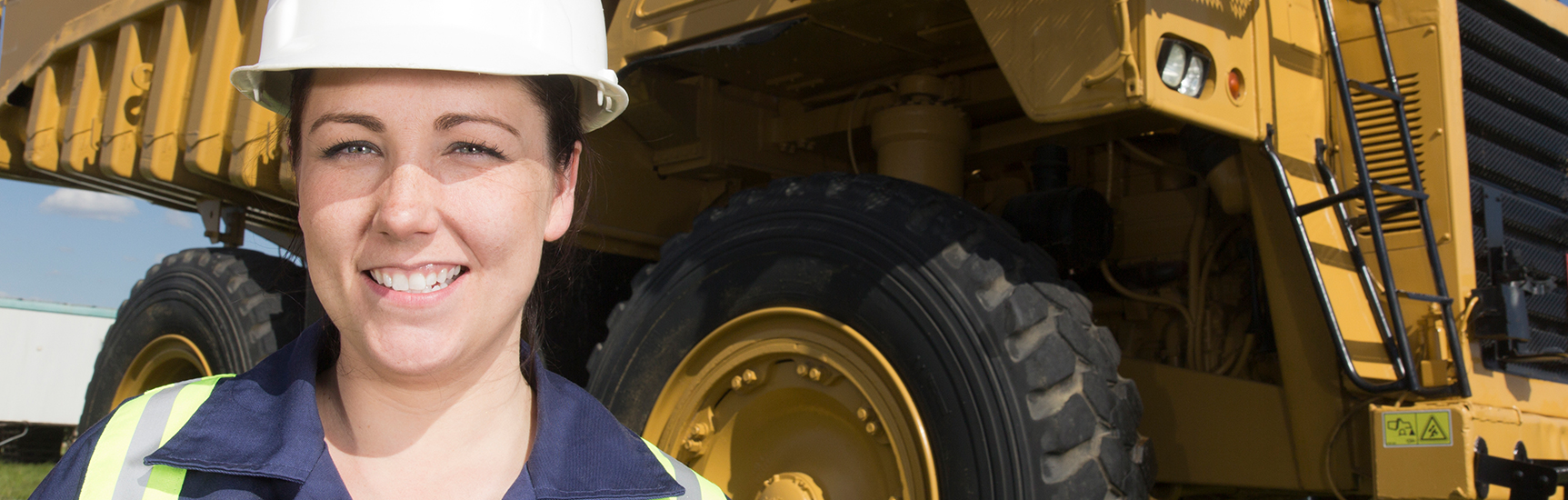 Happy mining apprentice standing in front of machinery